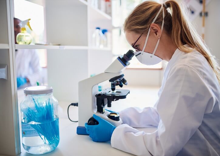 Female,Lab,Technician,Looking,At,Samples,Through,A,Microscope,While